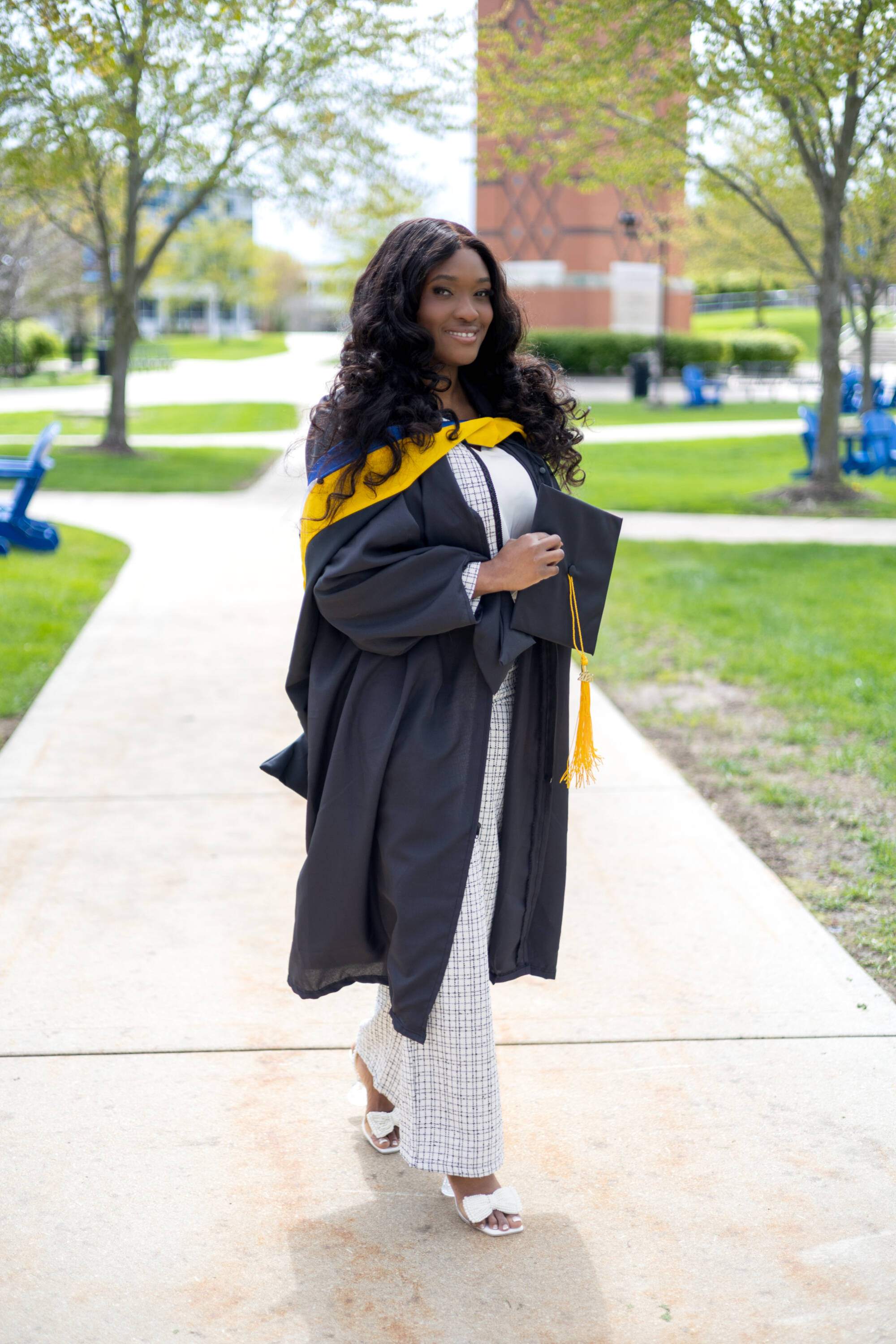 Student in front of gvsu clocktower in her graduation regalia